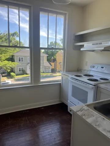 a kitchen that has a stove and a wooden floor