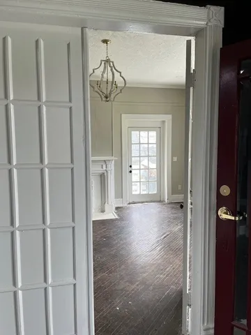 a view of a hallway with a wooden cabinet and chandelier