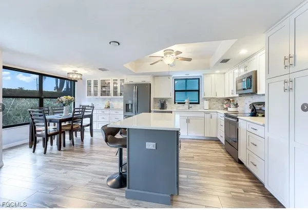 a large kitchen with cabinets wooden floor stainless steel appliances and dining table