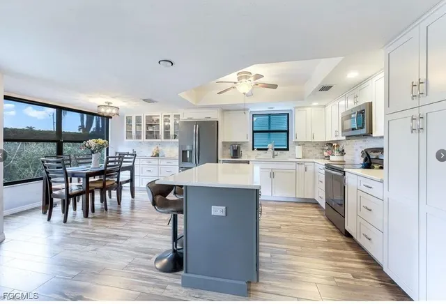 a large kitchen with cabinets wooden floor stainless steel appliances and dining table