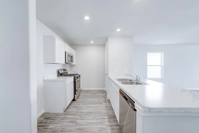 a large white kitchen with wooden floor