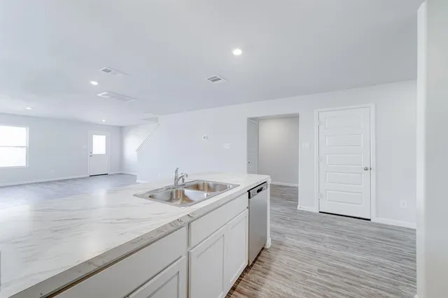 a kitchen with a sink a stove cabinets and wooden floor