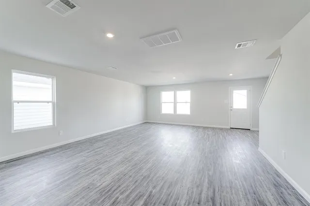 a view of empty room with wooden floor and window