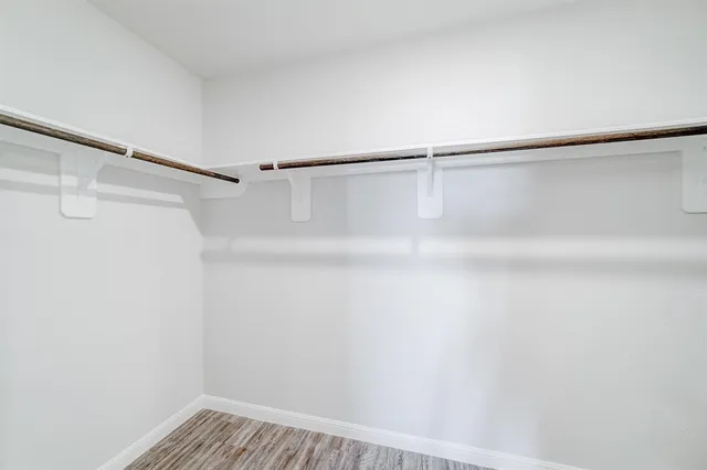 a view of an empty room with wooden floor and closet
