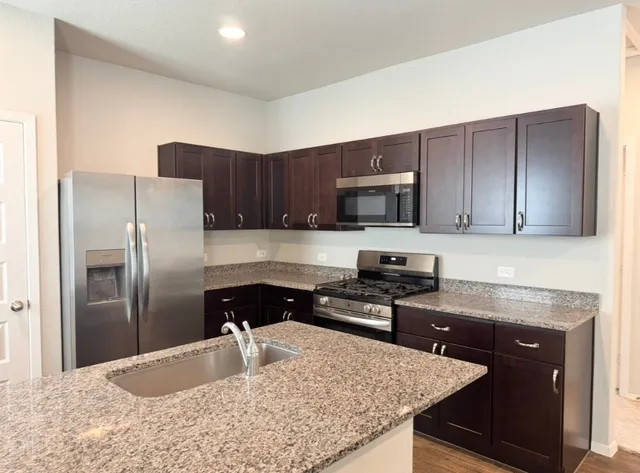 a kitchen with stainless steel appliances granite countertop a stove a sink and a microwave