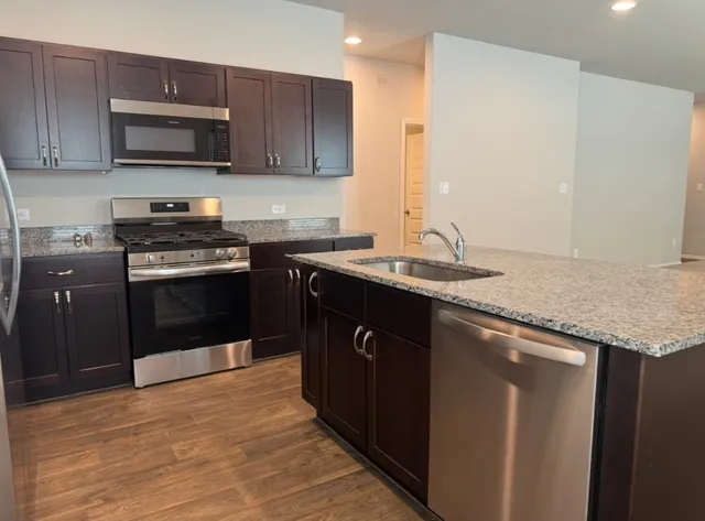 a kitchen with granite countertop wooden cabinets a refrigerator and a sink
