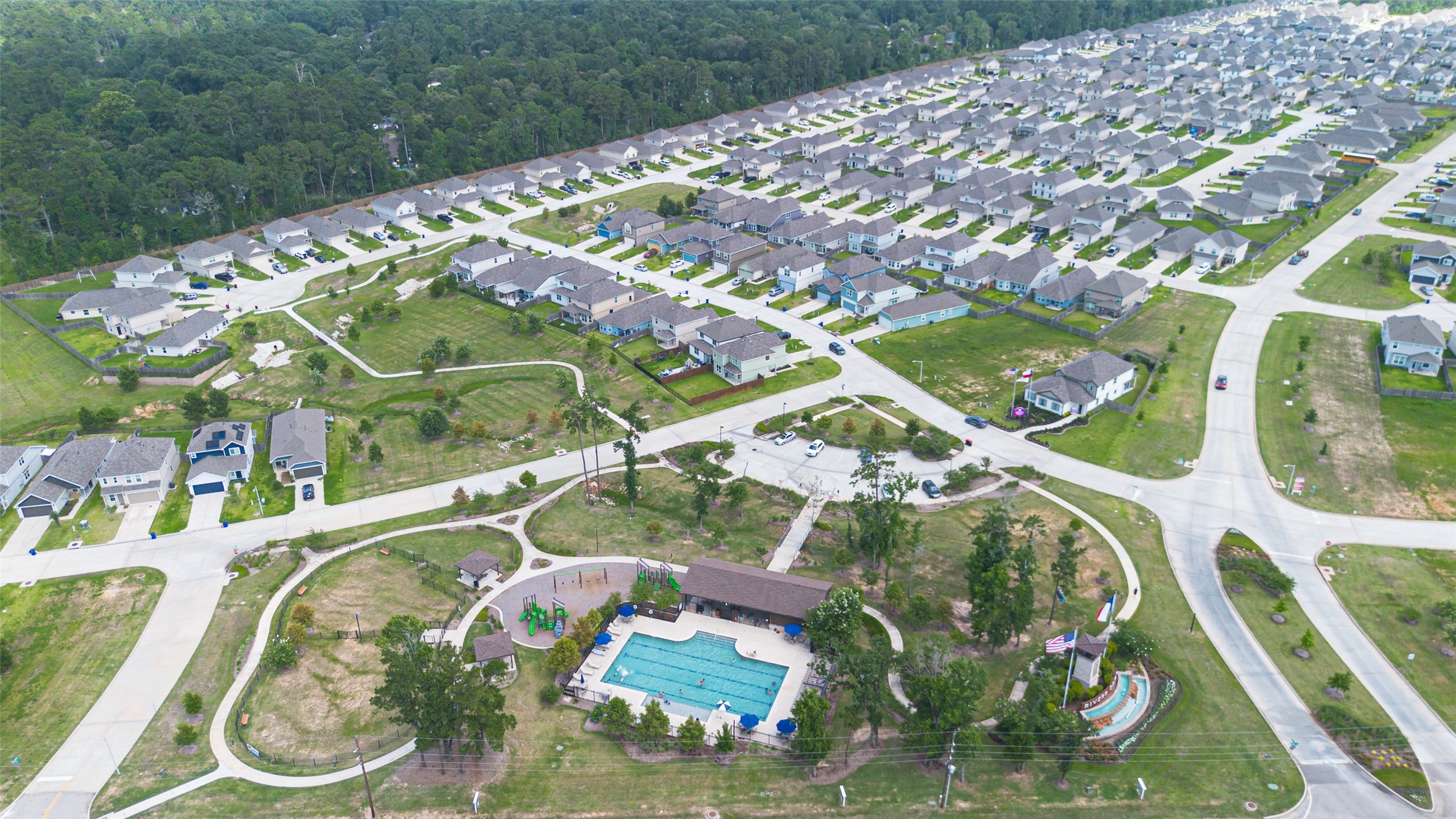 2526 Sturgeon Way Conroe, TX 77384 - Photo 46 of 49 This aerial photo showcases a large residential neighborhood with well-spaced, modern homes and green spaces. The area features a community pool and playground, offering recreational amenities. Streets are neatly laid out, providing easy access throughout the community, and the surrounding greenery adds a peaceful atmosphere.