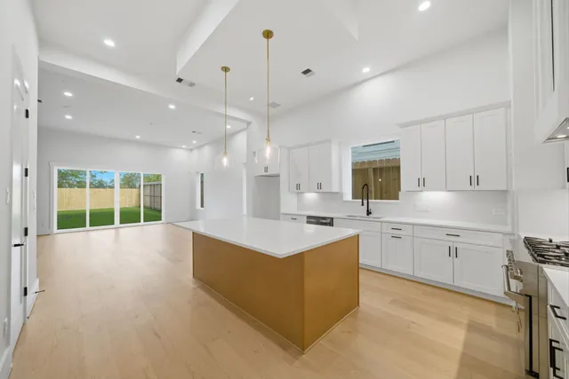 a large kitchen with stainless steel appliances kitchen island granite countertop a stove top oven a sink dishwasher and a cabinets