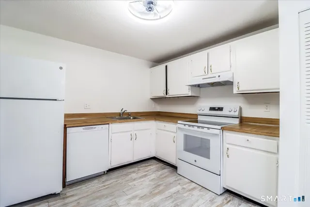 a kitchen with granite countertop white cabinets and white appliances