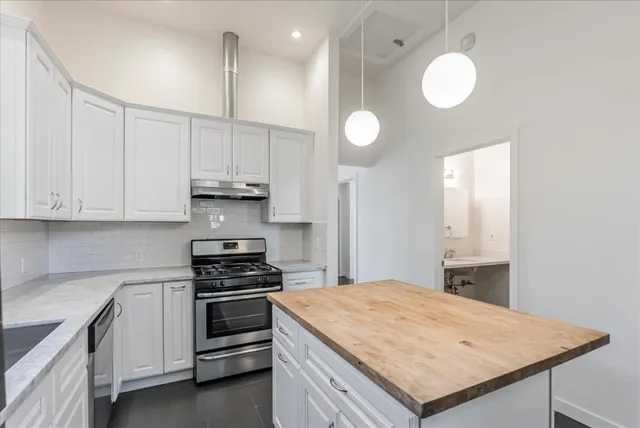 a kitchen with granite countertop a stove and white cabinets