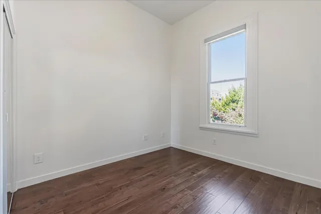 an empty room with wooden floor and window