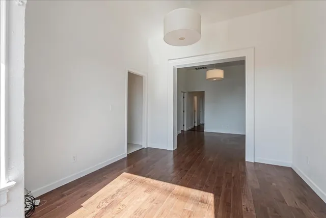 a view of a hallway with wooden floor and a bathroom