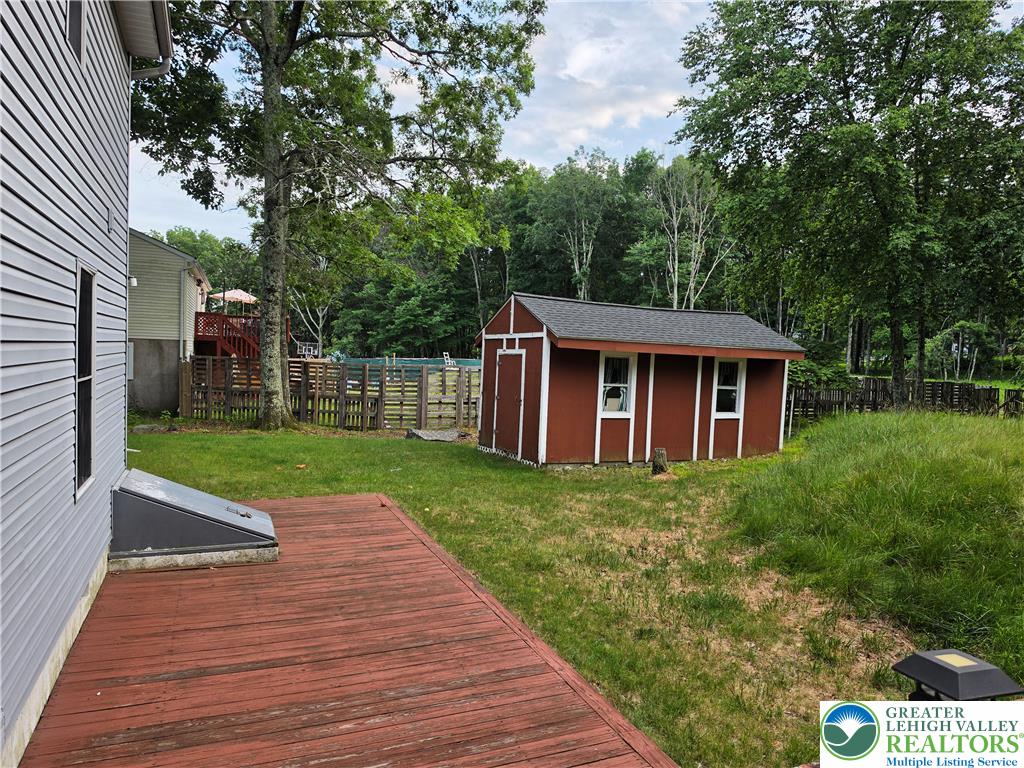 211 Murphy Circle Bushkill, PA 18324 - Photo 22 of 28 A quaint backyard featuring a classic red shed and a wooden deck, all encircled by lush greenery.