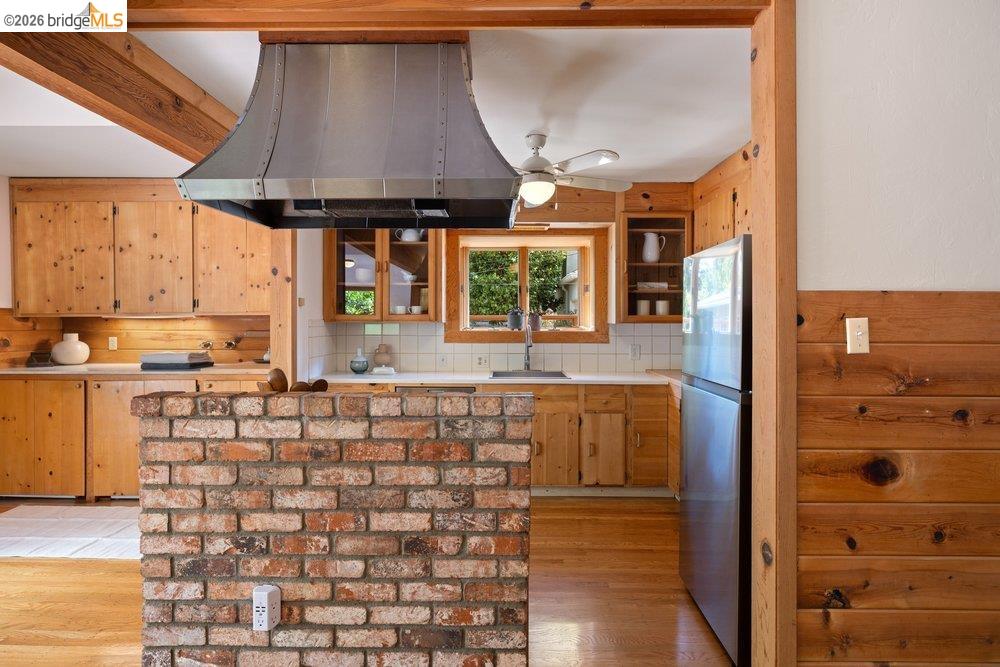 287 Purdue Avenue Kensington, CA 94708 - Photo 21 of 60 Kitchen featuring a brick half-wall, wood-finish cabinetry, stainless steel range hood, white countertops, and light wood-finish flooring