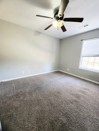 an empty room with windows and fan