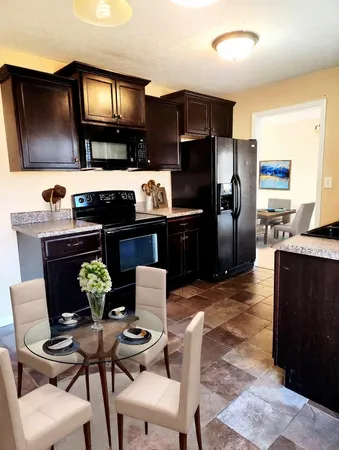 a kitchen with a table chairs refrigerator and microwave