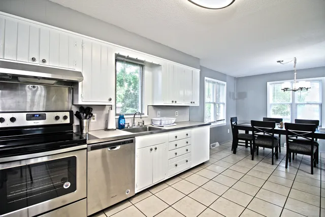 a kitchen with granite countertop cabinets a stove a sink and a dining table view