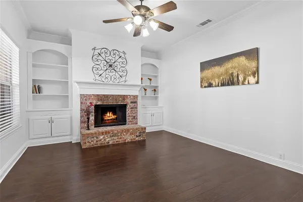 a view of a livingroom with a fireplace a ceiling fan and a wooden floor