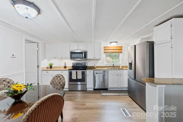 a kitchen with granite countertop stainless steel appliances a dining table and chairs