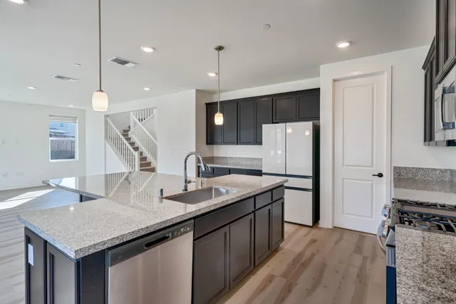 a kitchen with stainless steel appliances granite countertop a sink refrigerator and cabinets