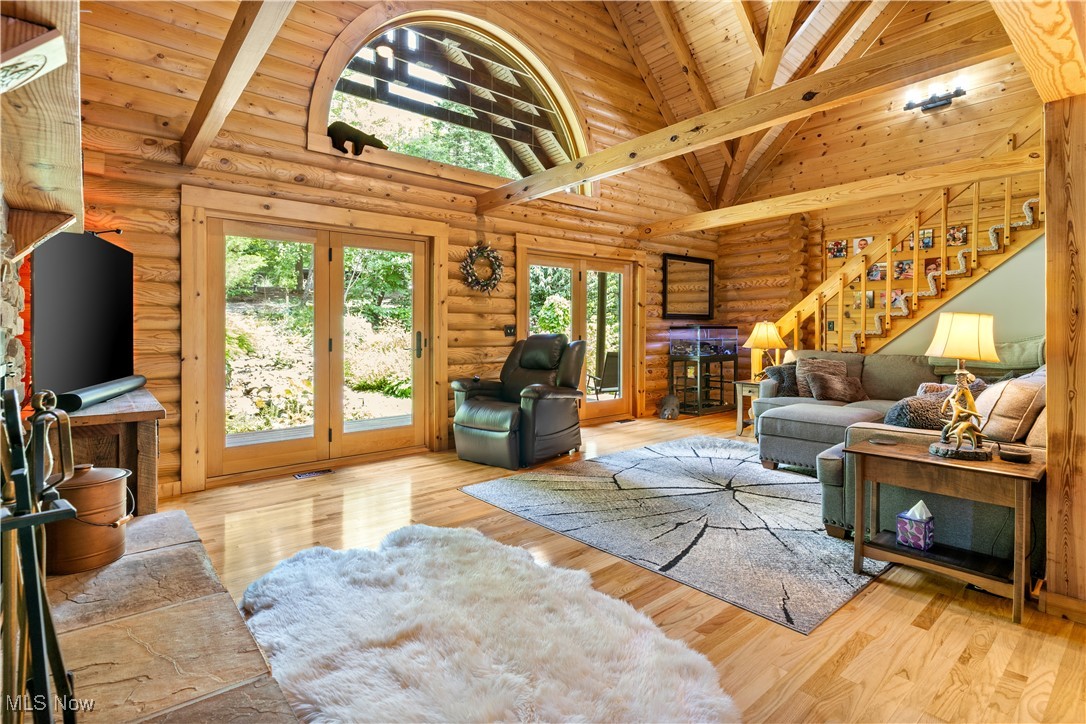 1784 North Medina Line Road Akron, OH 44333 - Photo 7 of 50 Living area with high vaulted ceiling, wood finished floors, stairway, rustic walls, and a wooden ceiling with exposed beams