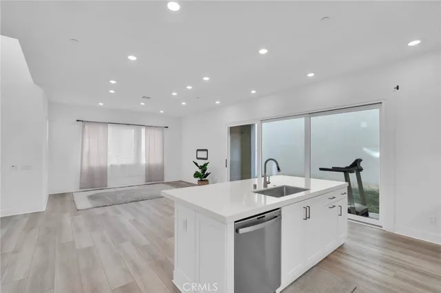 a kitchen with stainless steel appliances granite countertop a sink and a large mirror with wooden floor