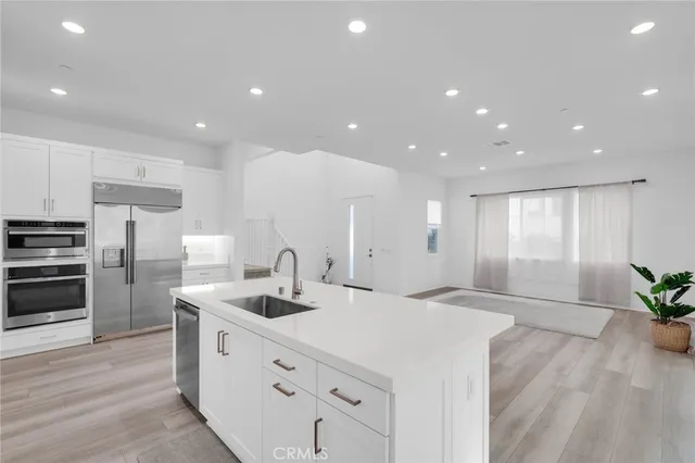 a large kitchen with stainless steel appliances a large counter top a stove a refrigerator and a sink