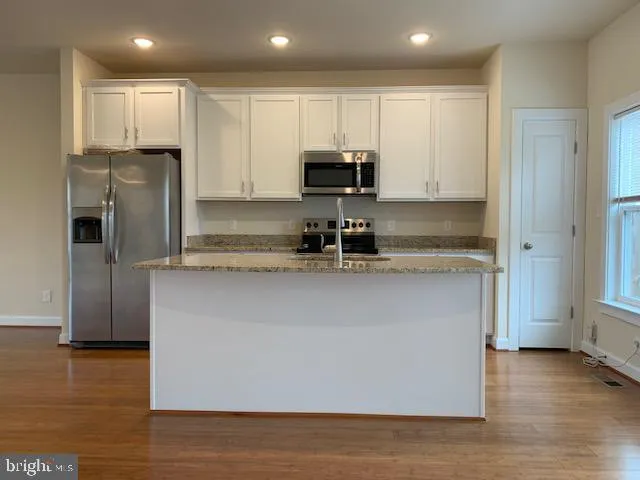 a kitchen with stainless steel appliances granite countertop a sink and a refrigerator