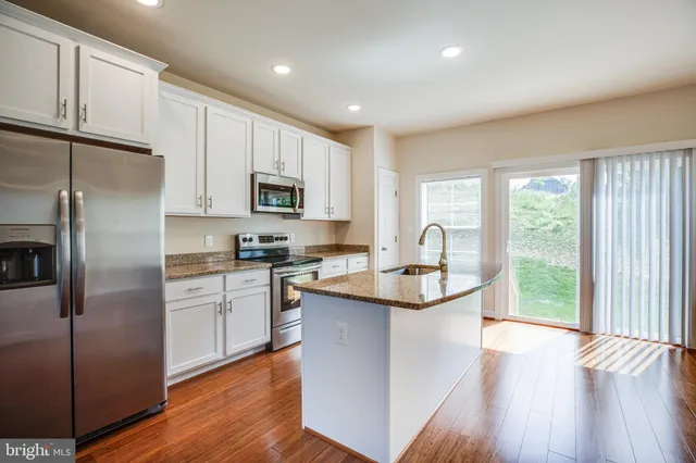 a kitchen with granite countertop a sink and a wooden floor