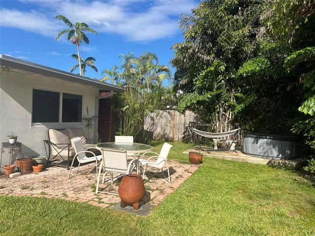 a view of a backyard with table and chairs potted plants and a palm tree