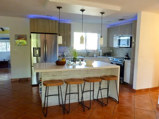 a kitchen with granite countertop a table chairs stove and refrigerator
