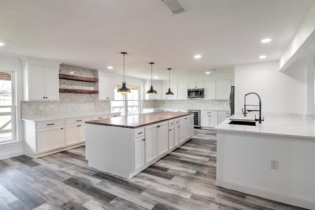 3884 Lois Road East Sanger, TX 76266 - Photo 10 of 40 a kitchen with kitchen island granite countertop a sink cabinets and wooden floor