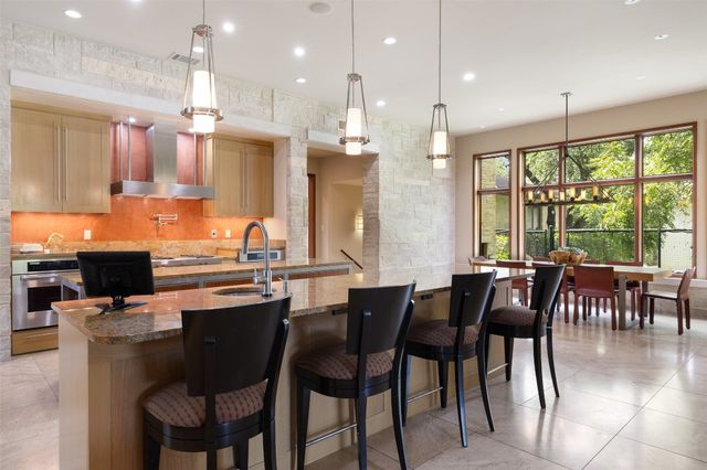 a kitchen with stainless steel appliances granite countertop a stove top oven a sink dishwasher a dining table and chairs with wooden floor