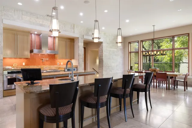 a kitchen with stainless steel appliances granite countertop a stove top oven a sink dishwasher a dining table and chairs with wooden floor