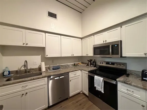 a kitchen with stainless steel appliances granite countertop white cabinets a sink and dishwasher