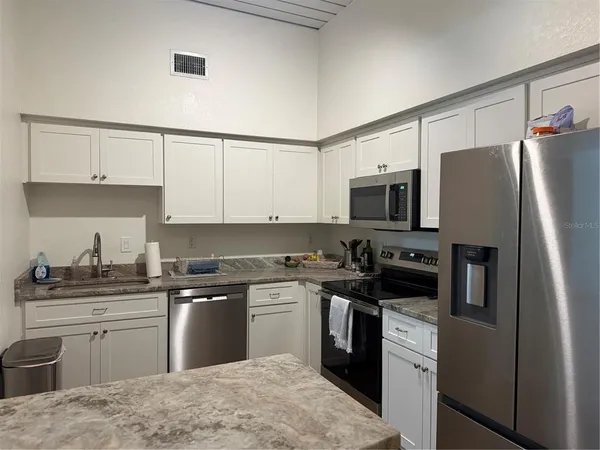 a kitchen with stainless steel appliances granite countertop a stove top oven a sink dishwasher a refrigerator and cabinets with wooden floor