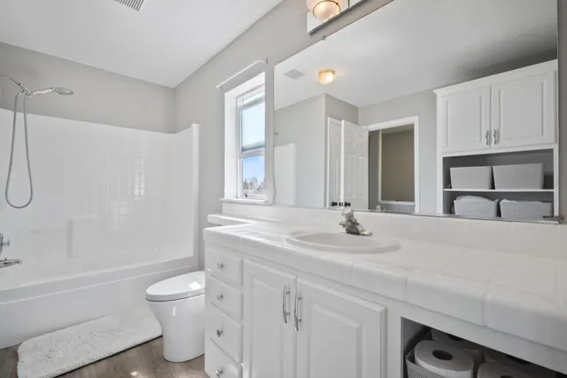 a spacious bathroom with a toilet a sink and a mirror