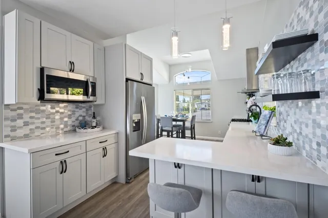 a kitchen with stainless steel appliances a dining table chairs microwave and sink