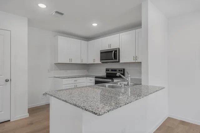 a kitchen with stainless steel appliances granite countertop a stove a sink and a microwave
