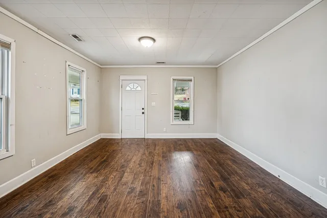 a view of an empty room with wooden floor and a window