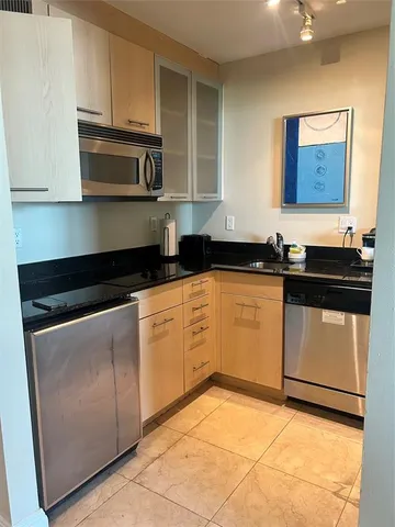 a kitchen with granite countertop a sink a stove top oven and cabinets