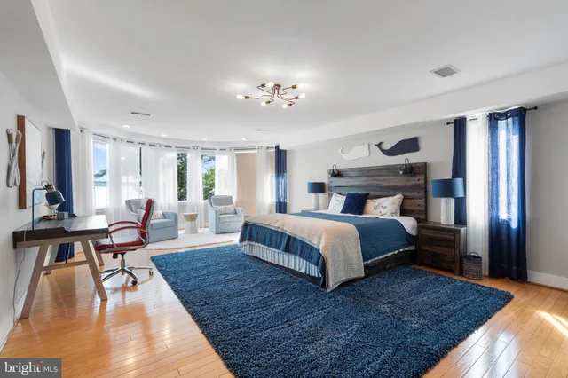 a spacious bedroom with a large bed a rug and windows