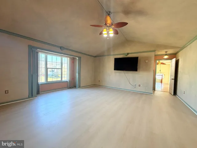 a view of an empty room with a window and a kitchen