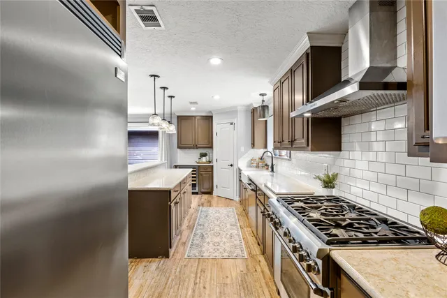 a kitchen with stainless steel appliances granite countertop a stove a sink dishwasher and a refrigerator