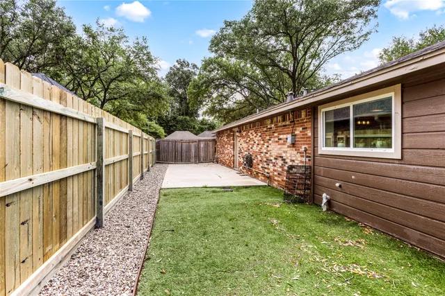 a view of a backyard with wooden fence and large trees