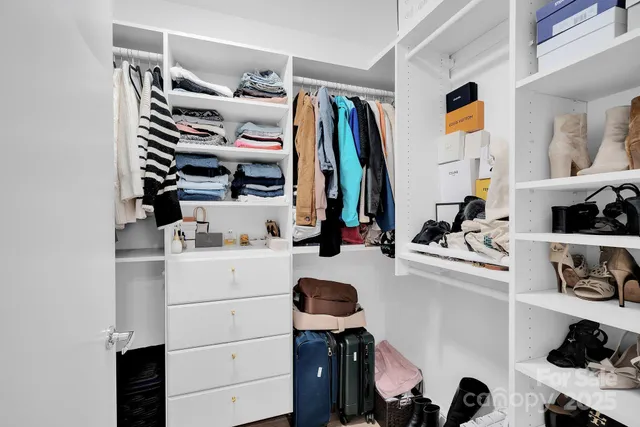 a view of walk in closet with clothes and shoes