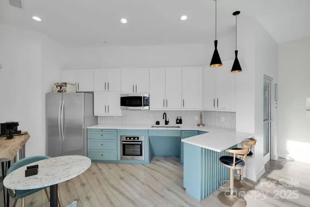 a kitchen with stainless steel appliances a stove a sink a microwave a refrigerator and cabinets