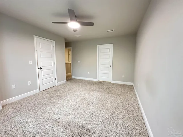 an empty room with closet and a ceiling fan