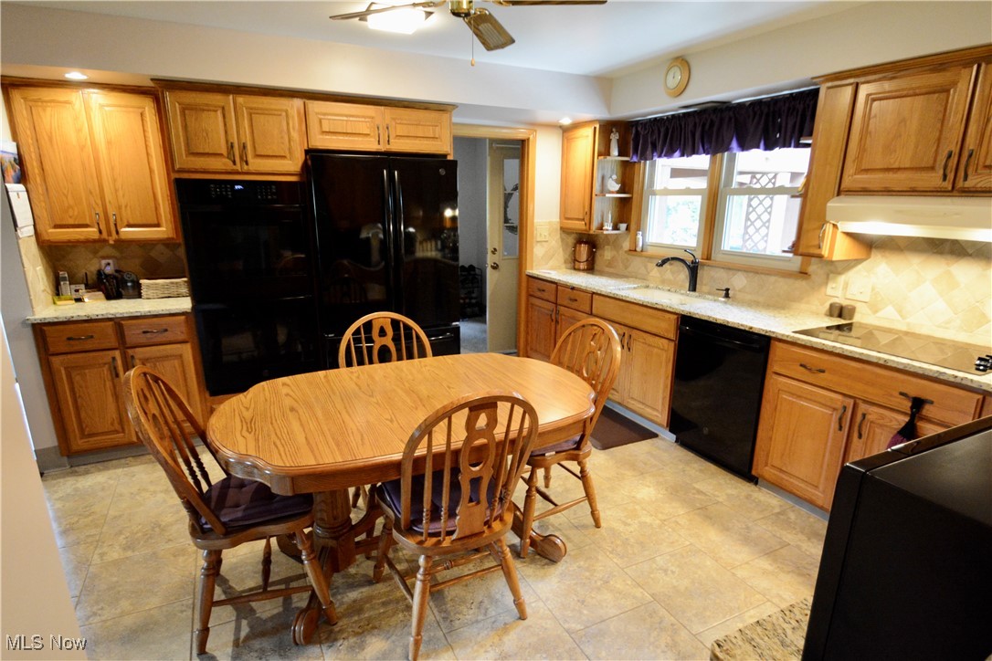 2724 Spitler Road Youngstown, OH 44514 - Photo 12 of 30 Kitchen featuring black appliances, under cabinet range hood, ceiling fan, and decorative backsplash