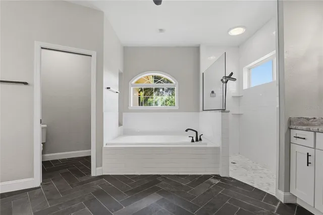 an empty room with a chandelier fan and windows